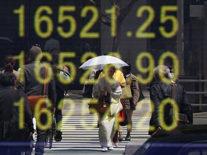 FILE PHOTO - Woman clad in a kimono is reflected in an electronic board displaying Japan's