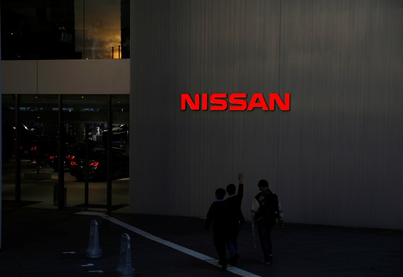 People walk near a Nissan signage at Nissan Motor Co.'s global headquarters in Yokohama, Japan