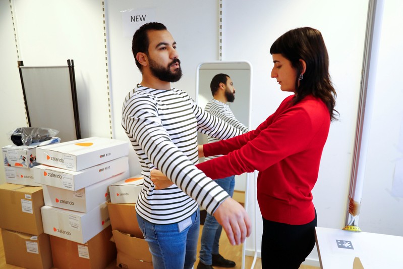 Fitting models checks out sizes of a t-shirt which goes on sale at the online shop of fashion