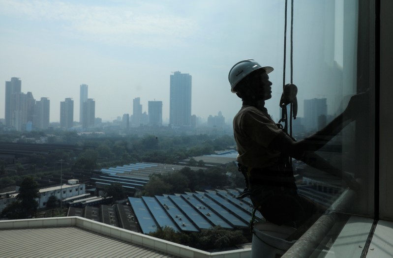 A worker cleans the exterior of an office building in Mumbai's central financial district