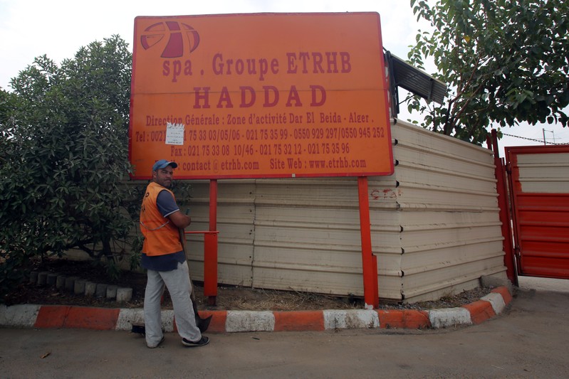 A worker stands in front of a sign for ETRHB Haddad group in Algiers