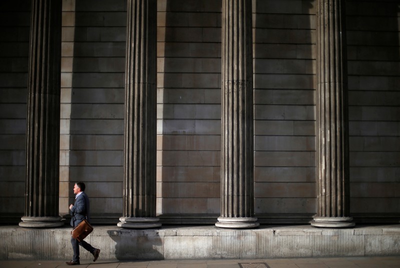 FILE PHOTO: A man walks past the columns of the Bank of England in the city of London