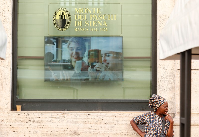 FILE PHOTO: A woman stands in front of the Monte dei Paschi bank in Rome