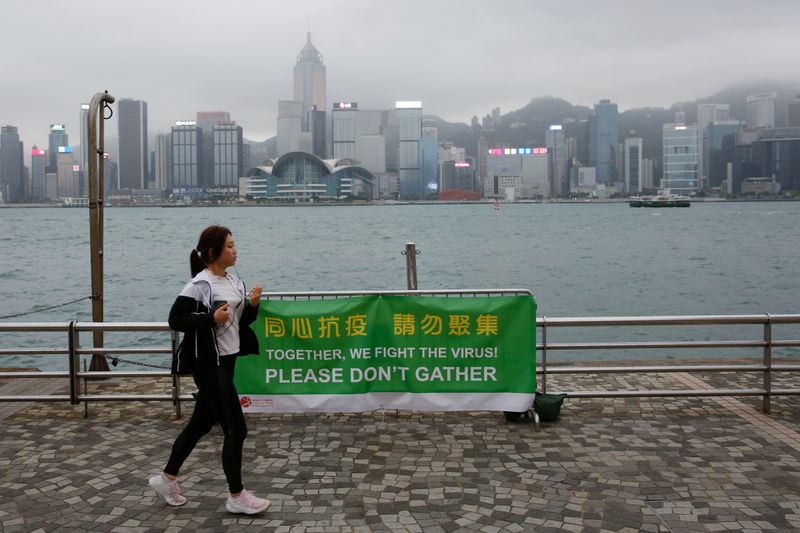 FILE PHOTO: A woman runs past a banner of health advice at Tsim Sha Tsui’s tourist