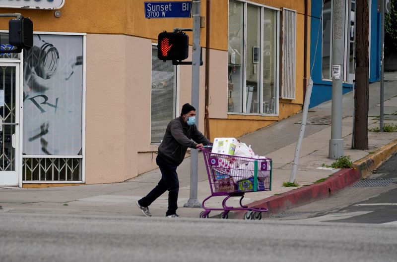 A shopper wearing a face mask moves a cart down Sunset Boulevard during the outbreak of the