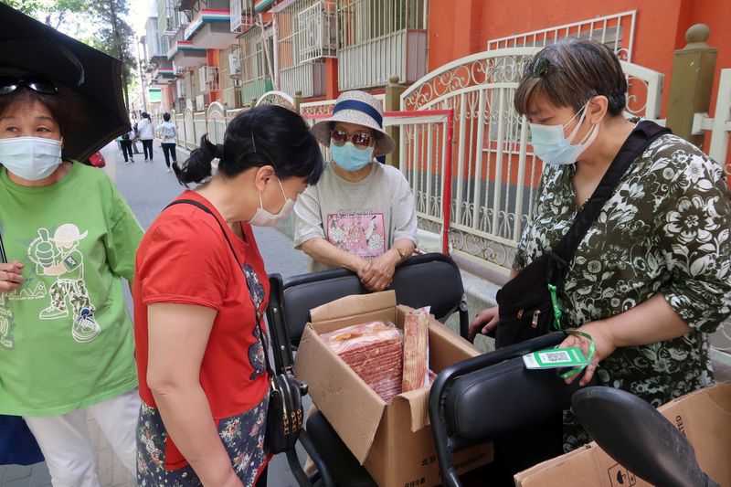 Street vendor Shan Peng attends to customers at her food stall set up on an electric tricycle