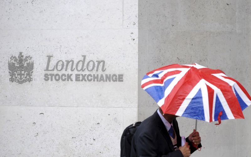 A worker shelters from the rain as he passes the London Stock Exchange in the City of London